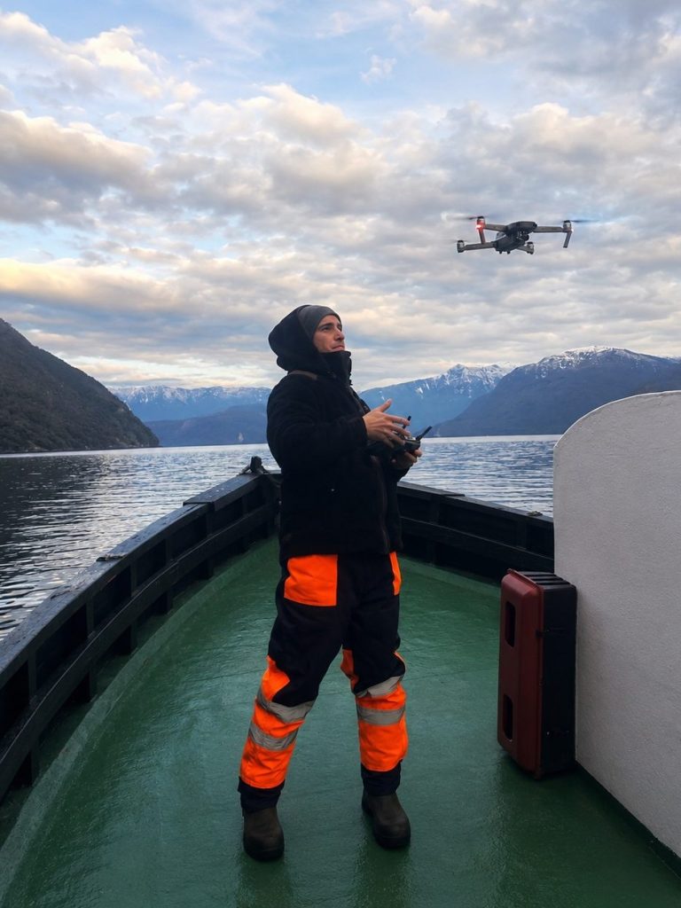 Piloto operando drone DJI en embarcacion en fiordo de la Patagonia